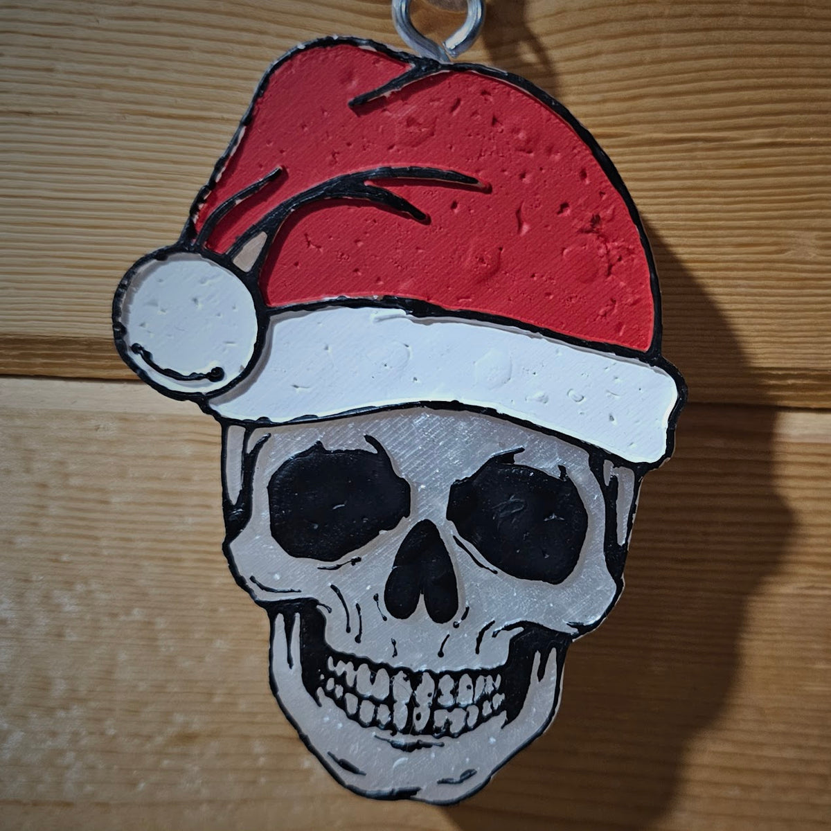 Skull freshie wearing a red Santa hat against wood