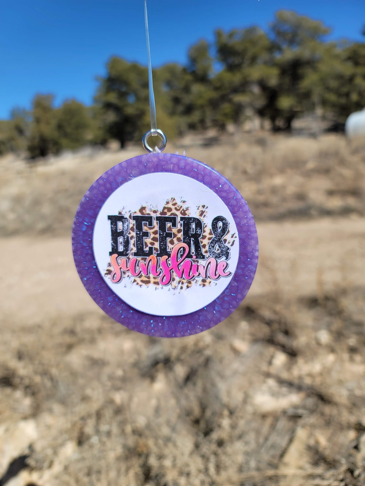 Purple round cardstock freshie with rodeo graphic hanging outdoors