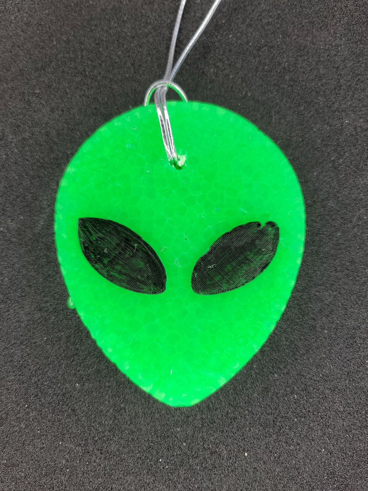 Neon green alien head freshie on dark background